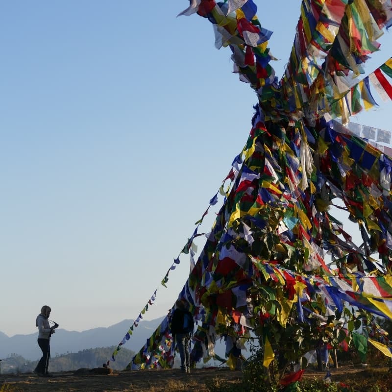 Woman standing next to a pile of prayer flags at Namobuddha