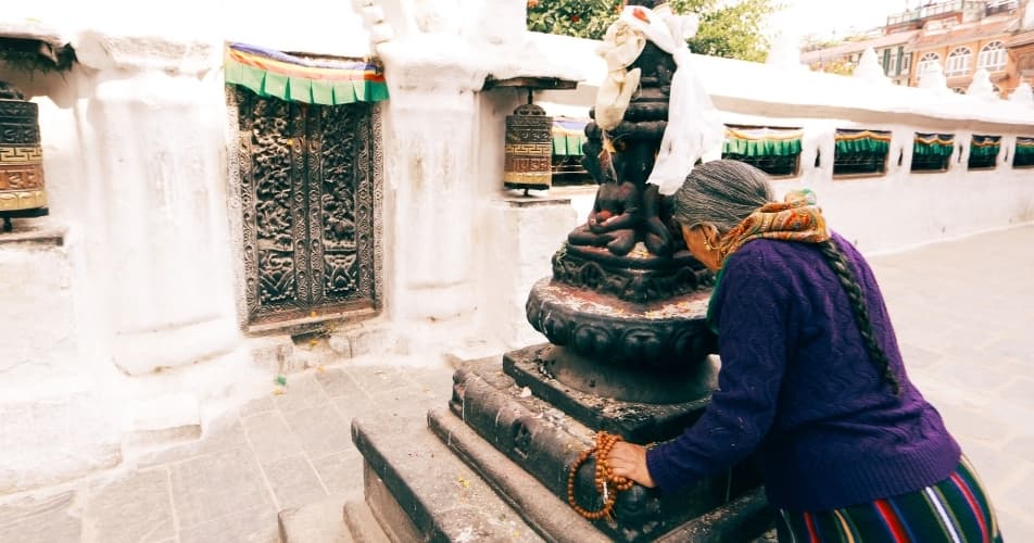 Tibetan lady doing puja at the Boudhanath temple in Nepal, spirituality is everywhere